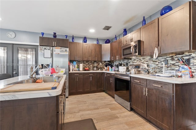 kitchen featuring stainless steel appliances, light countertops, visible vents, decorative backsplash, and a sink