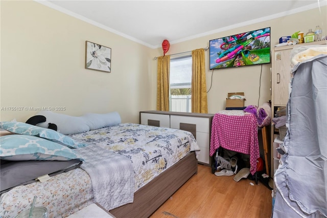 bedroom with wood finished floors and crown molding