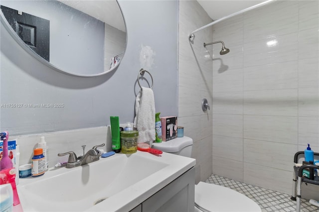 full bath featuring a tile shower, vanity, and toilet