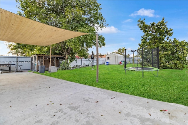 view of yard with a fenced backyard, an outbuilding, a trampoline, a storage unit, and a patio area