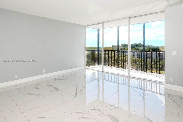 unfurnished room featuring expansive windows, marble finish floor, and baseboards