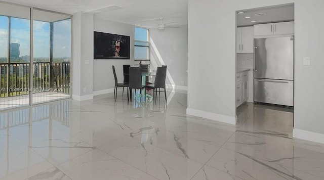 unfurnished dining area with marble finish floor, a wall of windows, a wealth of natural light, and baseboards