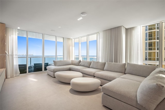 living room with expansive windows, a water view, and carpet flooring