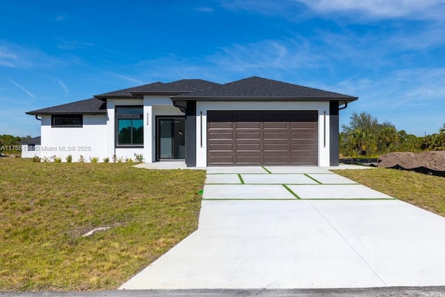 prairie-style house with a garage, driveway, a front lawn, and stucco siding