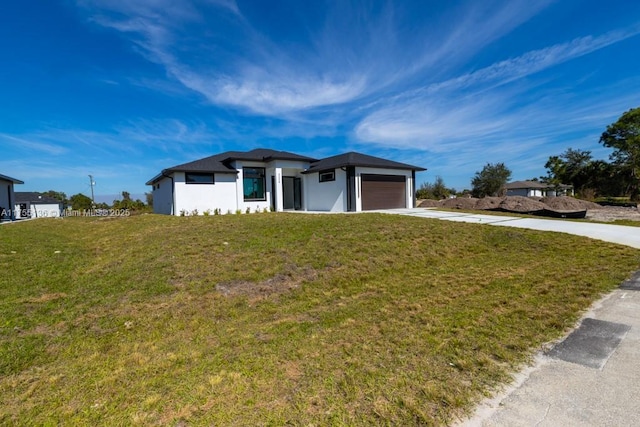 prairie-style home featuring a front yard, driveway, and an attached garage