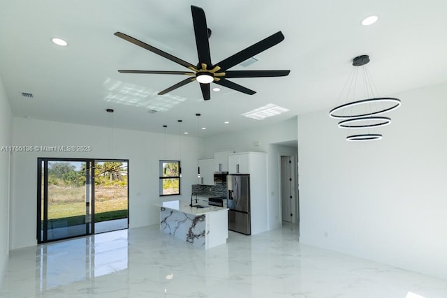 kitchen with appliances with stainless steel finishes, pendant lighting, white cabinets, and marble finish floor