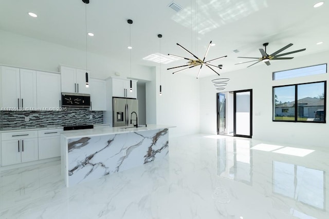 kitchen featuring marble finish floor, visible vents, open floor plan, a sink, and stainless steel fridge