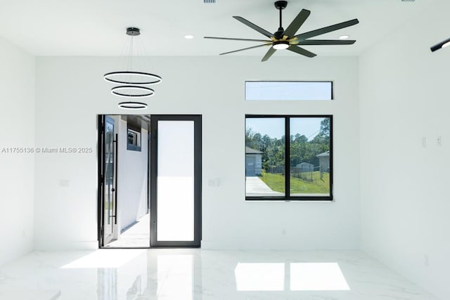 spare room with marble finish floor, ceiling fan with notable chandelier, and recessed lighting