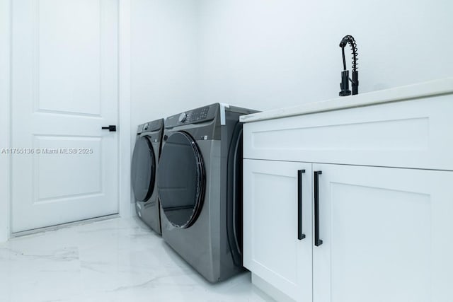 laundry area with marble finish floor, washer and clothes dryer, and cabinet space