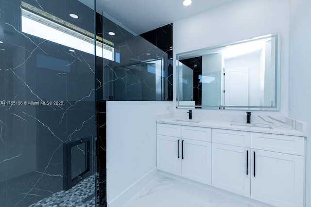 bathroom featuring marble finish floor, a sink, a marble finish shower, and double vanity