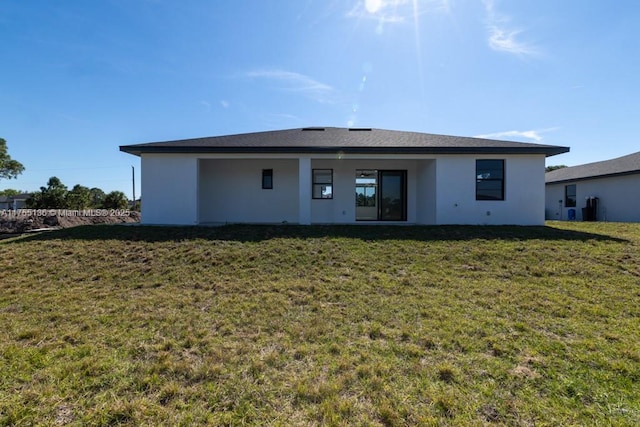 rear view of house featuring a yard and stucco siding