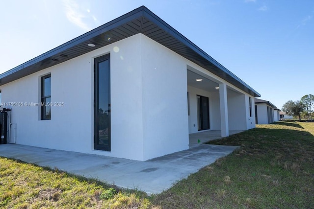 view of side of home featuring a yard and stucco siding