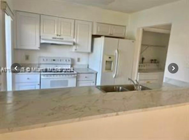 kitchen with light stone counters, white refrigerator with ice dispenser, a sink, range, and under cabinet range hood