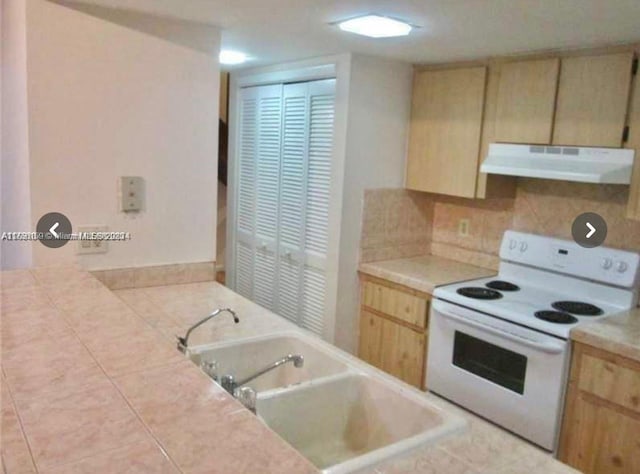 kitchen featuring under cabinet range hood, light brown cabinets, white range with electric stovetop, and a sink