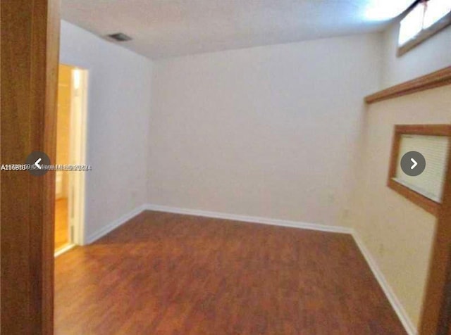 spare room featuring wood finished floors and baseboards