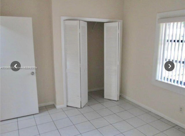 unfurnished bedroom with a closet, light tile patterned flooring, and baseboards