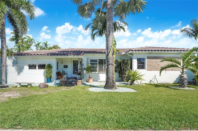 mediterranean / spanish home featuring a tiled roof, a front yard, and stucco siding