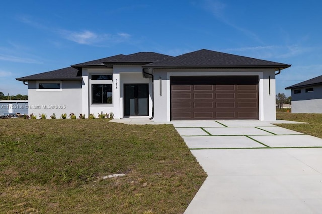 prairie-style house featuring a garage, a front yard, driveway, and stucco siding