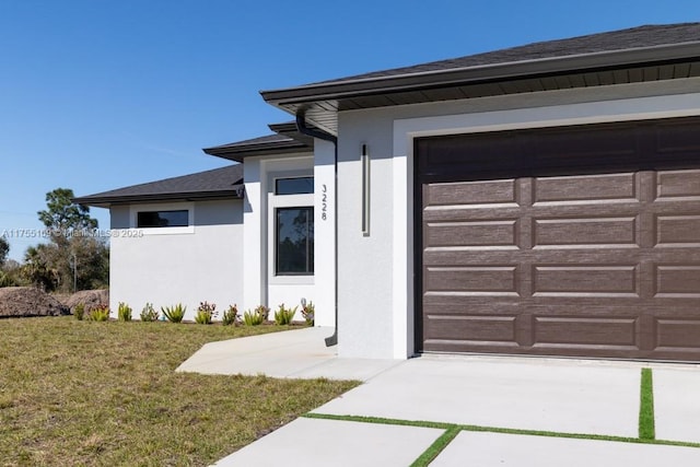 exterior space with a garage, a yard, and stucco siding