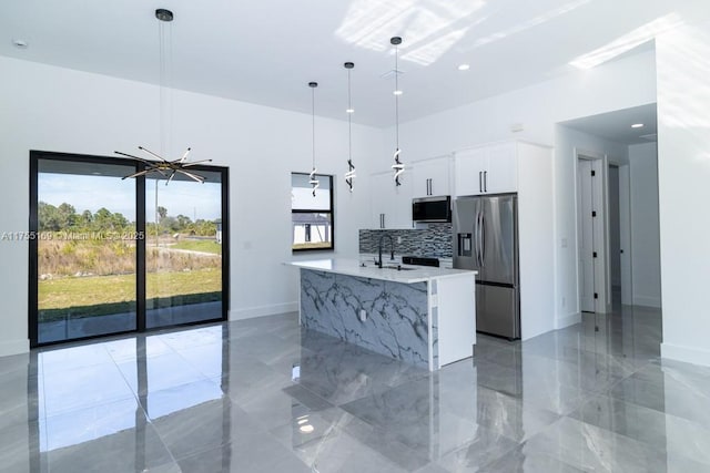 kitchen with marble finish floor, pendant lighting, light countertops, appliances with stainless steel finishes, and white cabinetry