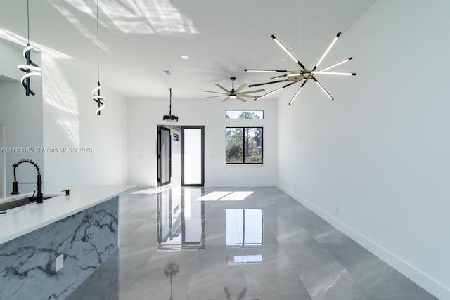 kitchen featuring marble finish floor, baseboards, open floor plan, and a sink