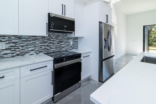 kitchen featuring white cabinets, light stone countertops, stainless steel appliances, concrete floors, and backsplash