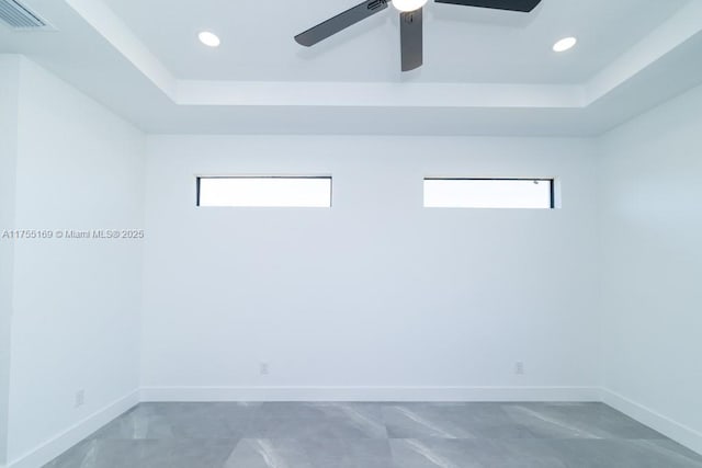 spare room featuring a wealth of natural light, a raised ceiling, visible vents, and baseboards