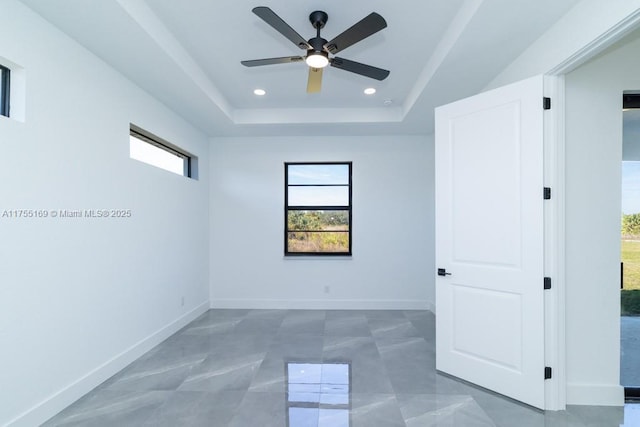 spare room with ceiling fan, baseboards, a tray ceiling, and recessed lighting