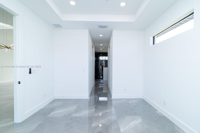 spare room featuring a raised ceiling, visible vents, and baseboards