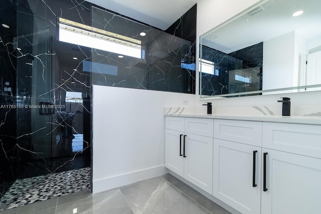 full bathroom with double vanity, marble finish floor, a marble finish shower, and a sink