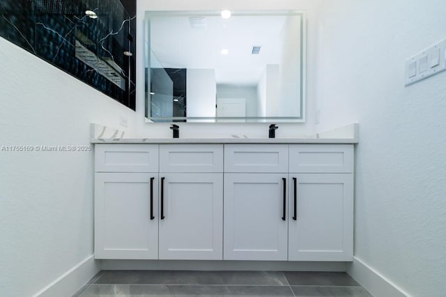 full bath featuring double vanity, a sink, visible vents, and baseboards