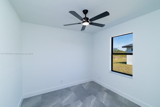 spare room featuring ceiling fan and baseboards