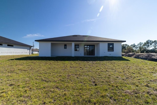 rear view of house with a lawn and stucco siding