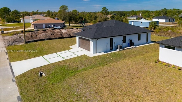 exterior space featuring a garage, driveway, central AC unit, and a front lawn