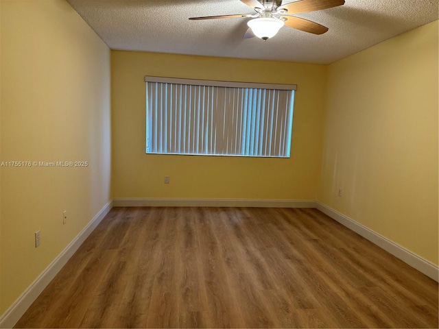 unfurnished room with a textured ceiling, wood finished floors, a ceiling fan, and baseboards