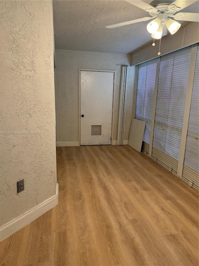 spare room with visible vents, a textured wall, a textured ceiling, wood finished floors, and baseboards