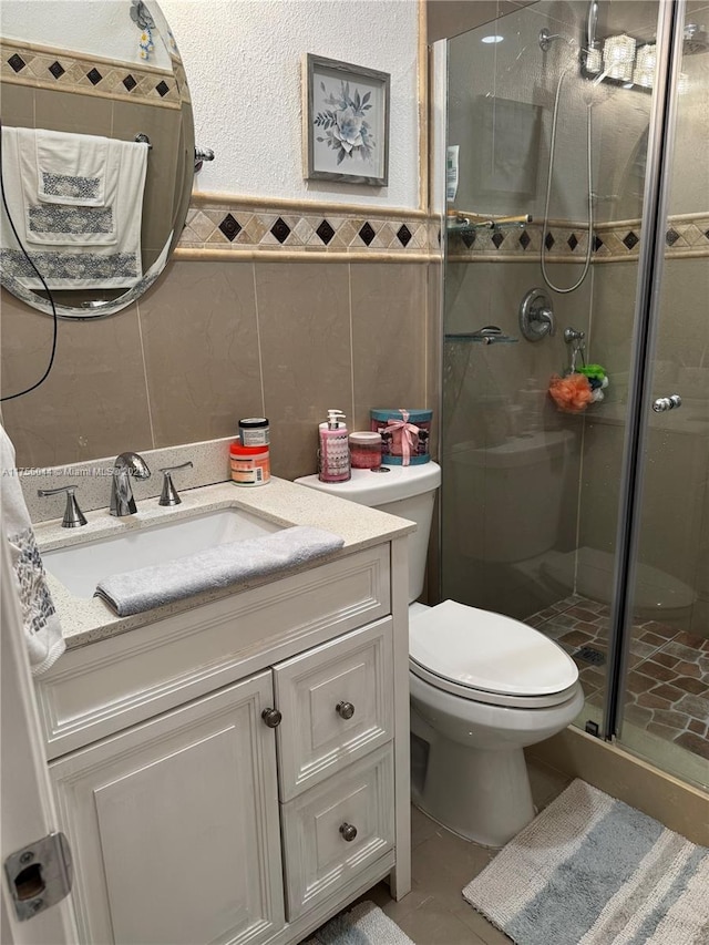 full bathroom featuring toilet, vanity, tile walls, wainscoting, and a shower stall