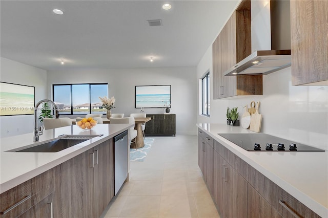 kitchen with modern cabinets, black electric stovetop, light countertops, wall chimney range hood, and a sink