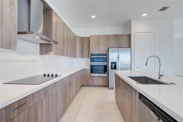 kitchen with light tile patterned floors, wall chimney exhaust hood, modern cabinets, appliances with stainless steel finishes, and a sink