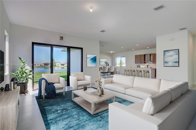 living area featuring recessed lighting, visible vents, a water view, and tile patterned floors