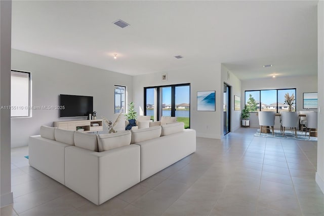 living room featuring light tile patterned floors, plenty of natural light, and visible vents