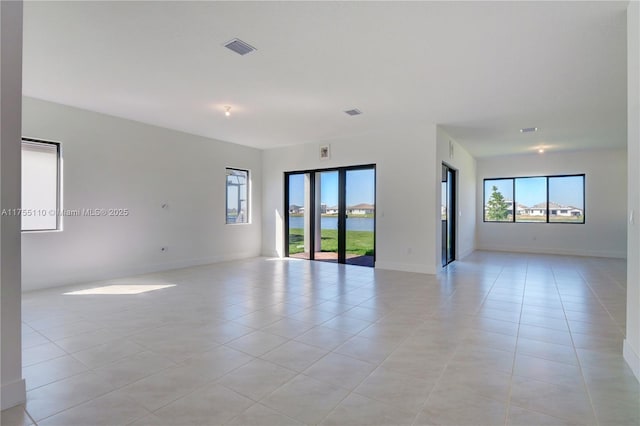 spare room with light tile patterned flooring, visible vents, and baseboards