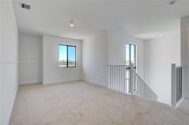 carpeted empty room with visible vents and baseboards