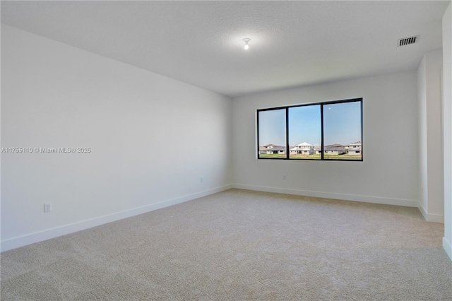 spare room featuring baseboards, a textured ceiling, visible vents, and light colored carpet