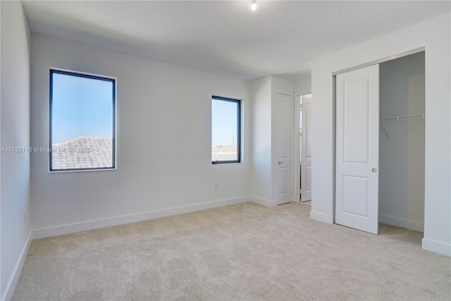 unfurnished bedroom with carpet, a closet, a textured ceiling, and baseboards