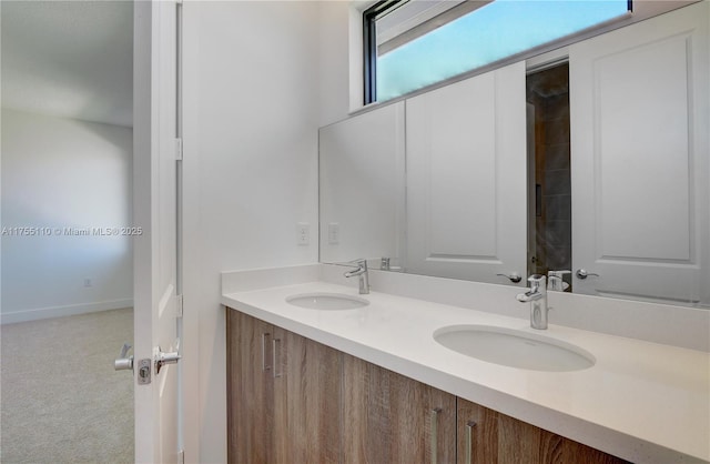 bathroom with double vanity, baseboards, and a sink