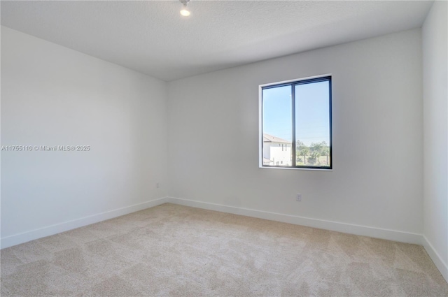 carpeted empty room featuring a textured ceiling and baseboards