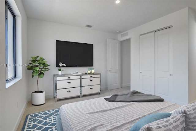 carpeted bedroom featuring a textured ceiling, a closet, visible vents, and baseboards