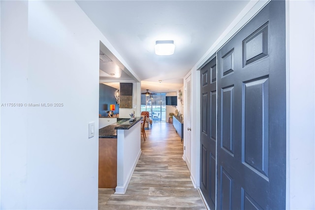 hallway featuring visible vents, baseboards, and light wood-style floors