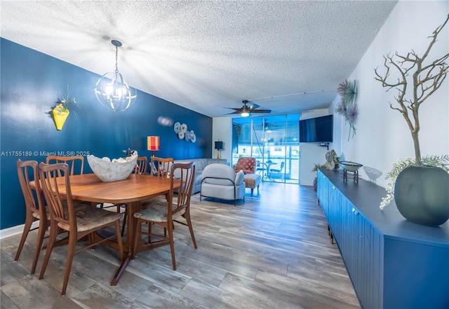 dining area with a wall of windows, a textured ceiling, wood finished floors, and ceiling fan with notable chandelier